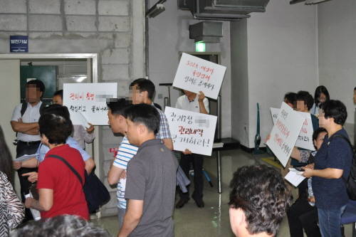 지난 7월18일 진행된 홍대 M오피스텔 정기총회 당시 비대위 소속 소유주들이 관리인 측에 피켓을 든 채 항의하고 있다. = 김경태 기자