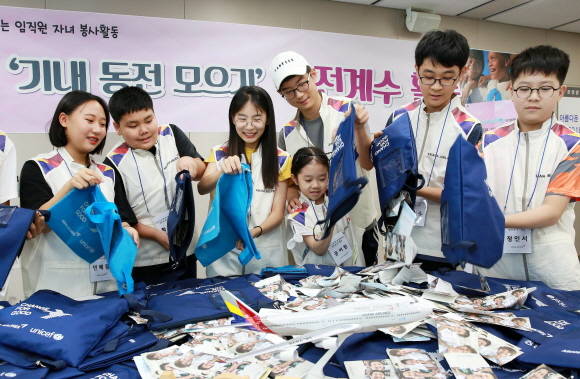 아시아나항공 교육훈련동에서 여름방학을 맞아 임직원 자녀들이 '사랑의 기내 동전 모으기 캠페인'으로 모인 동전의 계수 봉사활동에 참여하고 있다. ⓒ 아시아나항공