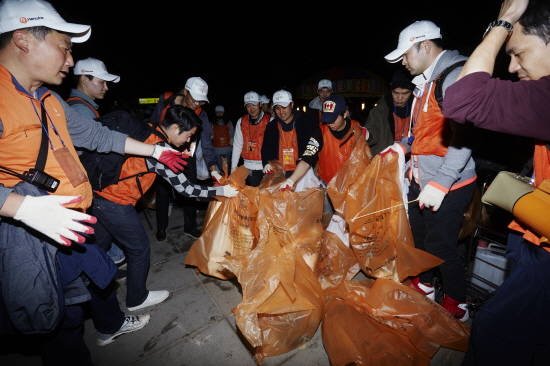한화 임직원 700명을 포함한 시민자원봉사자 1400명이 밤늦게까지 쓰레기를 수거하며 클린캠페인(환경정화활동)을 펼치는 모습. ⓒ 한화