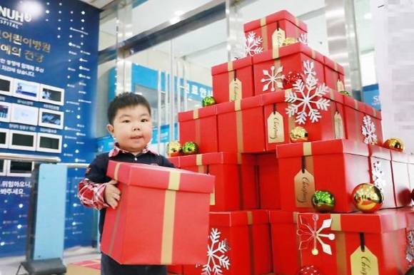 소원나무(위시트리) 이벤트에 참여한 어린이 환자가 크리스마스 선물 소원을 빌며 상자를 쌓고 있어요. ⓒ 한화갤러리아