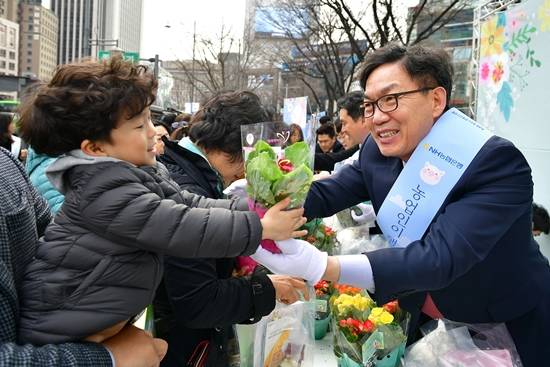 새봄맞이 고객사랑 가두캠페인에 참가한 이대훈 은행장이 아이에게 화분을 건네고 있다. ⓒ NH농협은행