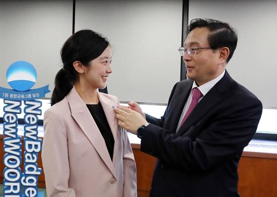 손태승 우리금융 회장(오른쪽)이 직원에게 새로 디자인한 그룹 배지를 달아주고 있다.ⓒ 우리금융그룹