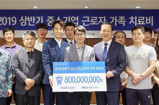 12일 을지로 기업은행 본점에서 김도진 은행장(앞줄 오른쪽 두 번째)과 이정재 홍보모델(앞줄 왼쪽 두 번째), 중소기업 근로자 가족들이 치료비 전달식을 마치고 기념촬영을 하고 있다. ⓒ IBK기업은행