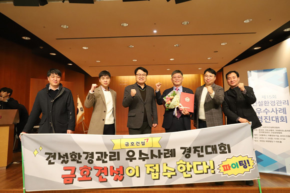 금호산업 직원들이 국회의장 상 수상 후 응원 플래카드 앞에서 기념사진을 찍고 있다. 왼쪽 4번째가 사례를 발표한 이정우 고속국도 창녕~밀양간 건설공사 6공구 현장소장. ⓒ 금호산업