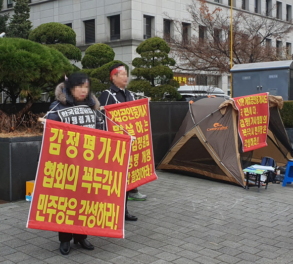 공인중개사협회 소속 공인중개사들이 한국감정원에 '부동산거래질서교란행위 신고센터'를 설치하는 것을 반대하는 시위를 벌이는 모습. 준비한 피켓 중 한국감정원과 다른 단체인 '감정평가사협회'가 등장한다. = 장귀용 기자
