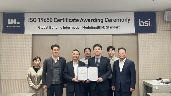 'ISO 19650' 인증 수여식 행사 사진. 박유신 DL건설 주택건축사업본부장(앞줄 좌측 세번째)과 임성한 BIS코리아 대표(앞줄 좌측 네번째) 등 관계자들이 기념 촬영하고 있다. © DL건설