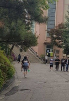 오른쪽 발에 깁스를 한 이를 업고 언덕을 올라가는 한 학생. 문제는 앞에 계단이 나타났다는 것. = 임혜현 기자