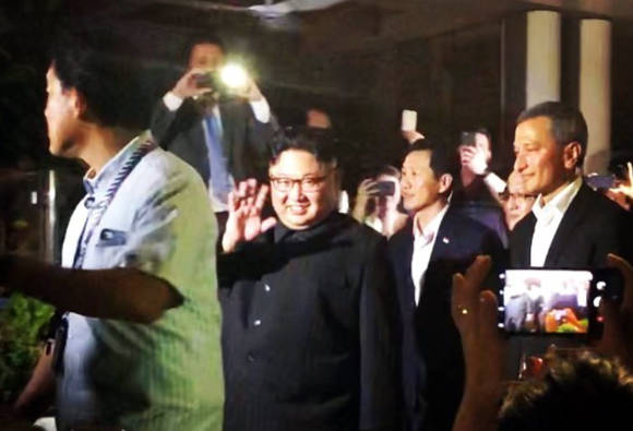 김정은 북한 국무위원장이 북미정상회담을 하루 앞둔 11일(현지시간) 저녁 싱가포르 마리나 베이 샌즈 호텔을 방문해 관광객들을 향해 손을 흔들며 밝게 웃고 있다.(SNS 캡처) ⓒ 뉴스1