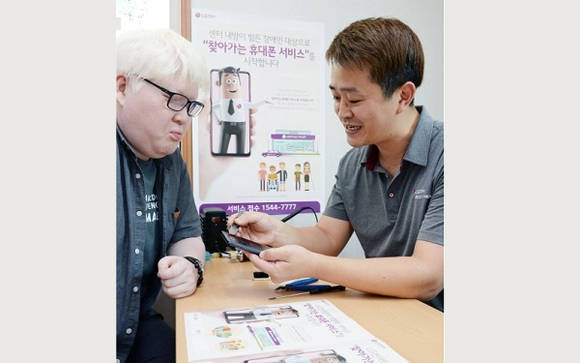 백색증과 저시력 장애를 가진 사람이 LG전자 '찾아가는 휴대폰 서비스'를 신청해 스마트폰 수리를 받고 있어요. ⓒ LG전자