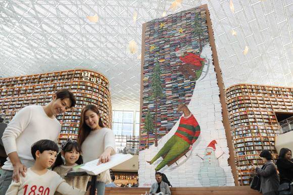 5일 오전 서울 삼성동 스타필드 코엑스몰 별마당 도서관에 크리스마스 시즌을 앞두고 1만4000여권의 책을 쌓아 만든 초대형 '별마당 북트리'가 선을 보인 가운데 모델과 아이들이 북트리에 대한 안내책자를 읽고 있다. ⓒ 이마트