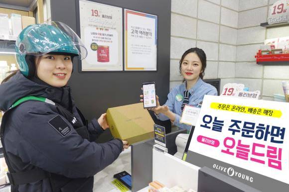 고객이 올리브영 온라인몰에서 주문한 상품을 주소지 인근 매장 직원이 포장해 배송 담당자에게 전달하고 있다. ⓒ CJ올리브네트웍스