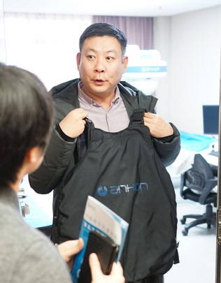 왕지안리 본부장이 몸소 캡슐 내시경 장비를 입어 보고 있다. 뒤쪽으로 정보 판독 기기도 보인다. 캡슐을 삼킨 뒤 일정한 복장을 통해 각종 내부 정보를 얻어내는 것이다. ⓒ 프라임경제