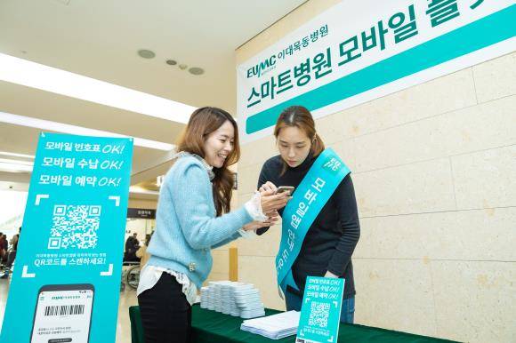 방문객을 대상으로 도우미가 이대목동병원 스마트 앱 설치를 도와주고 있다. ⓒ 이화의료원