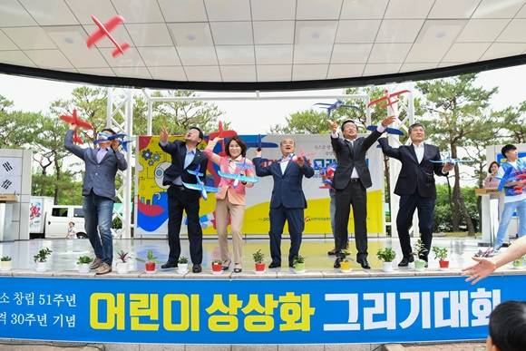 '제1회 어린이 상상화 그리기 대회'에 참석한 관계자들이 모형비행기를 날리고 있다. ⓒ 광양제철소