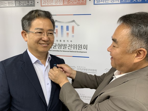송재호 대통령직속 국가균형발전위원장이 이용빈 자문위원에게 배지를 달아주고 있다. ⓒ 더불어민주당 광산갑지역위원회