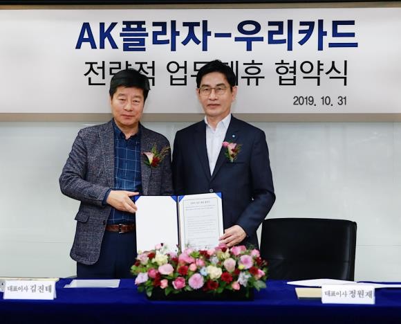 AK플라자가 우리카드와 공동 마케팅 추진을 위한 업무 협약을 지난달 31일 체결했다. 사진은 김진태 AK플라자 대표이사(왼쪽)와 정원재 우리카드 사장이 업무협약 체결 후 기념 사진을 촬영하고 있다. ⓒ AK플라자