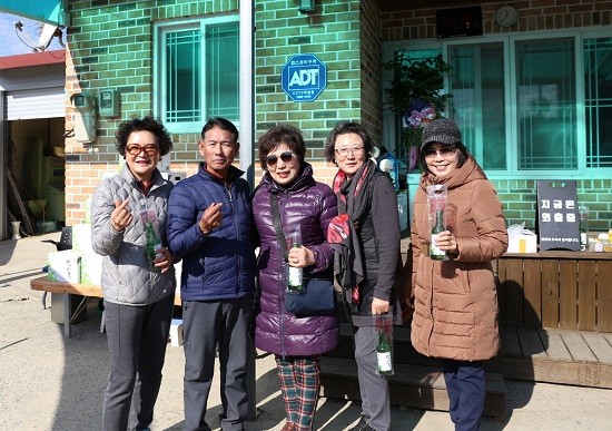 송가인 씨 부친 조연환(왼쪽 두 번째)씨가 송가인 고향집을 찾은 방문객들에게 잎새주를 나눠주며 기념촬영을 하고 있다. ⓒ 보햐양조