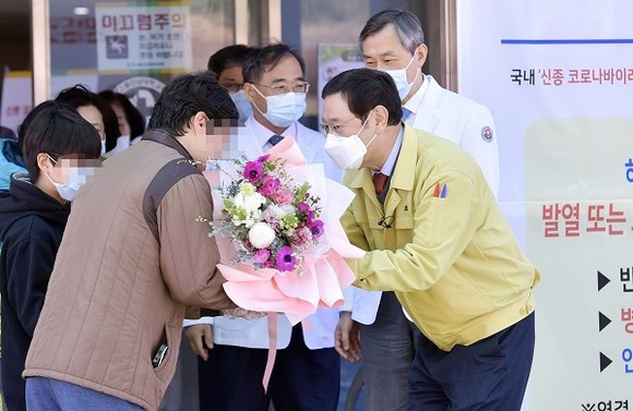이용섭 광주광역시장이 11일 오전 남구 빛고을전남대병원에서 치료를 받고 퇴원하는 코로나19 대구 확진자 가족들에게 꽃다발을 전하고 있다. ⓒ 광주광역시