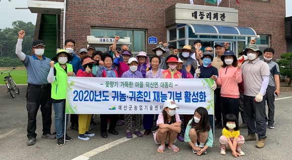 귀농·귀촌인과 원주민 화합의 '꽃향기 그윽한 마을 만들기' 행사을 실시 후 기념촬영을 하고 있다. ⓒ 예산군