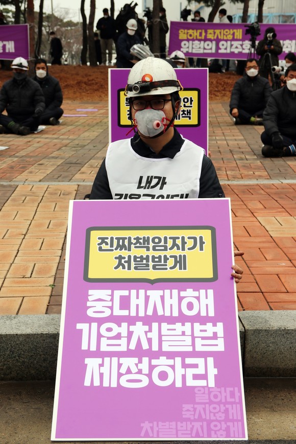 10일 태안화력발전소에서 열린 '고 김용균 2주기 현장 추모제'에서 태안화력 비정규직 노동자가 '중대재해기업처벌법 제정하라'는 피켓을 들고 있다. ⓒ 연합뉴스