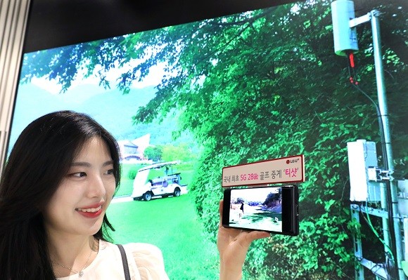LG유플러스 모델이 레인보우힐스CC에 구축된 5G 28㎓ 기지국 현장 사진을 배경으로 U+골프 서비스를 감상하는 모습. ⓒ LG유플러스