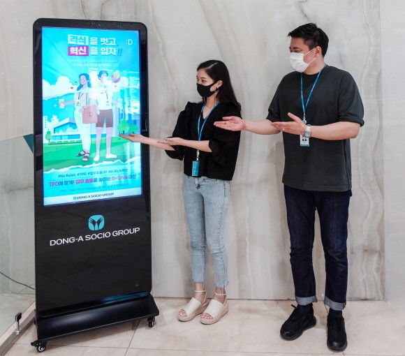 동아쏘시오그룹 직원들이 자율복장제 시행을 알리는 포스터 옆에서 사진촬영을 하고 있다. © 동아쏘시오홀딩스