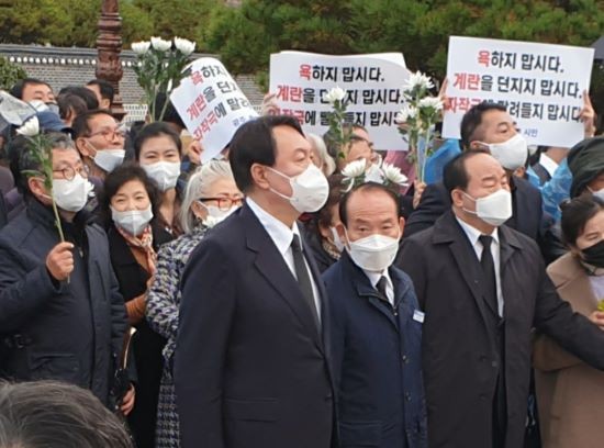 추모탑에서 진입하지 못하고 있는 윤석열 후보 주위에 일부 광주시민들이 '욕하지 맙시다. 계란 던지지 맙시다. 자작극에 말려들지 맙시다'라고 쓴 손 팻말을 들고 질서 유지를 당부하고 있다. ⓒ 프라임경제