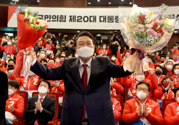 윤석열 대통령 당선인이 10일 새벽 서울 여의도 국회도서관에 마련된 '국민의힘 제 20대 대통령선거 개표상황실'을 찾아 꽃다발을 받은 후, 취재진을 향해 포즈를 취하고 있다. ⓒ 연합뉴스