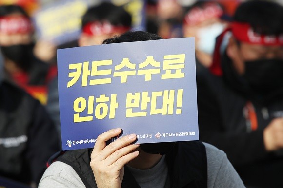 지난해 11월 정부서울청사 앞에서 열린 카드노동자 총파업 결의대회에서 한 참석자가 '카드수수료 인하 반대' 손팻말을 들고 있다. ⓒ 연합뉴스