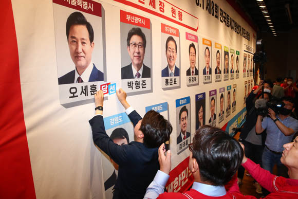 국민의힘 지도부가 지난 1일 국회 도서관 대강당에 마련된 지방선거 개표상황실에서 당선이 유력시되는 단체장 후보 사진 밑에 스티커를 붙이고 있다. ⓒ 연합뉴스