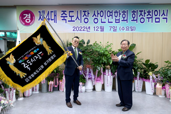 최일만 전 상인회장(우측)이 신임 박태용회장(좌측) 상가번영회기를 전달하고 있다. = 김진호 기자