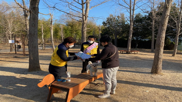 반려동물 지도요원이 공원에서 동물 등록 펫티켓 안내를 배부하고 있다. ⓒ 진주시