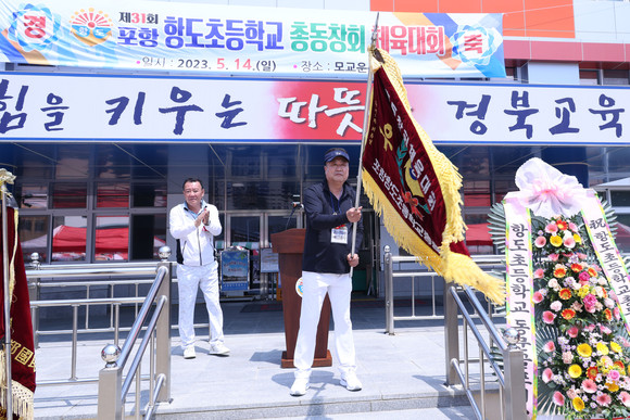 14일 포항항도초등총동창회 체육대회에서 김종우 회장이 우승기를 흔들고 있다. = 김진호 기자