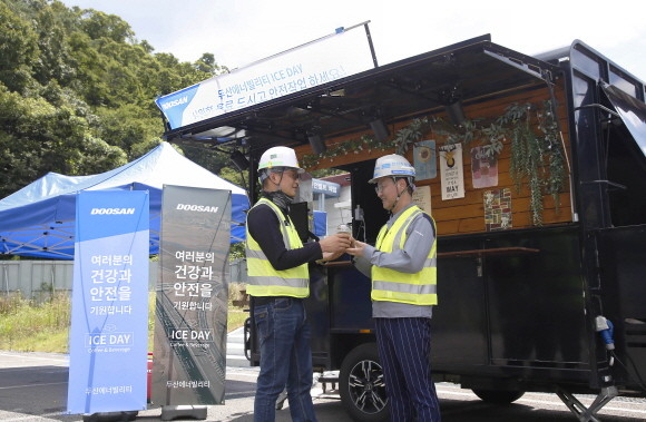 함양-창녕간 고속도로 건설현장에서 이형도 두산에너빌리티 소장(오른쪽)이 직원에게 커피를 전달하고 있다. ⓒ 두산에너빌리티