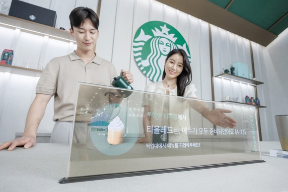 LG디스플레이 모델이 스타벅스와 협업한 매장용 투명 OLED 콘셉트를 소개하고 있다. ⓒ LG디스플레이
