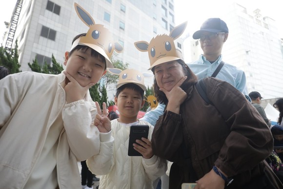 가족과 즐기면 더욱 재미있는 Pokémon GO City Safari: 서울, 이브이 선바이저를 착용한 어머니와 자녀가 함께 이벤트를 플레이하고 있다. ⓒ 나이언틱