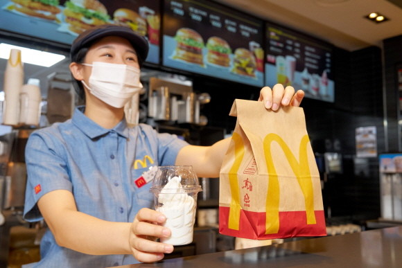 한국맥도날드 매장 직원이 친환경 재생페트(rPET) 컵에 담긴 '선데이 아이스크림'을 고객에게 건네는 모습. © 맥도날드