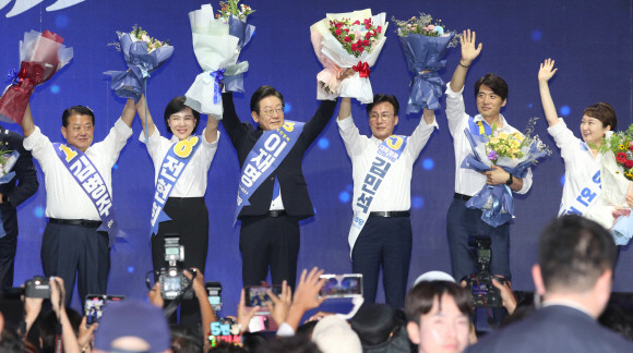 더불어민주당 당 대표 연임이 확정된 이재명 신임 대표와 새 최고위원들이 18일 서울 송파구 올림픽공원 KSPO돔에서 열린 전국당원대회에서 꽃다발을 들고 당원들에게 인사하고 있다. ⓒ 연합뉴스