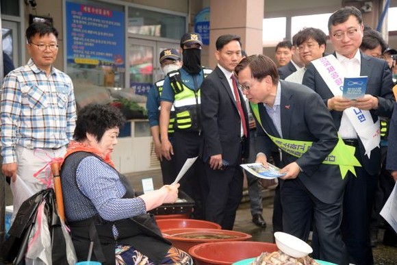 고광완 광주광역시 행정부시장과 공직자들이 지난 5월24일 오일장이 열리는 무안읍 장터에서 민·군 통합공항 이전 효과 등을 홍보한 가운데 한 상인이 홍보물을 읽어보고 있다. ⓒ 광주광역시