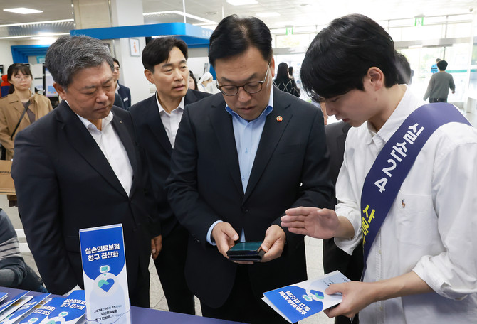 25일 실손보험 청구 전산화가 시행된 가운데 김병환 금융위원장이 홍보 부스에 방문해 현장 안내직원의 설명을 듣고 있다. ⓒ 금융위원회