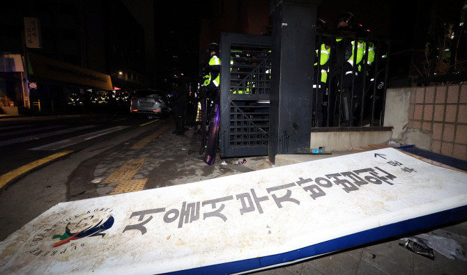 윤석열 대통령이 내란 우두머리 혐의로 구속되자 일부 지지자들이 서울 마포구 서울서부지방법원을 습격한 19일 오전 경찰이 서부지법 후문에 현판이 쓰러져 있다. ⓒ 연합뉴스