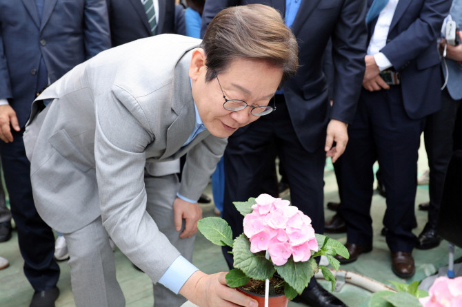 이재명 더불어민주당 대선 경선 후보가 25일 전남 나주시 전남농업기술원 에너지자립형 온실을 방문해 꽃을 살펴보고 있다. ⓒ 연합뉴스