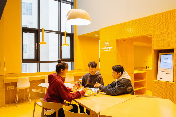 코리빙 브랜드 '맹그로브(MGRV)' 공용공간에서 입주민들이 음식을 나눠 먹는 모습. © MGRV