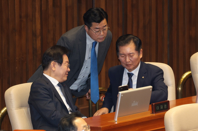 이재명 대통령(당시 더불어민주당 대표)과 박찬대 민주당 원내대표(가운데), 정청래 민주당 의원(오른쪽)이 작년 9월 대정부 질문이 진행된 국회 본회의장에서 휴대전화를 함께 보며 대화하고 있다. ⓒ 연합뉴스