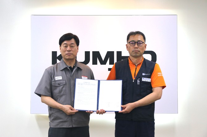 김명선 금호타이어 생산기술총괄 부사장(왼쪽)과 황용필 금호타이어지회 대표 지회장이 노사 특별합의문을 들고 사진을 찍고 있다. ⓒ 금호타이어