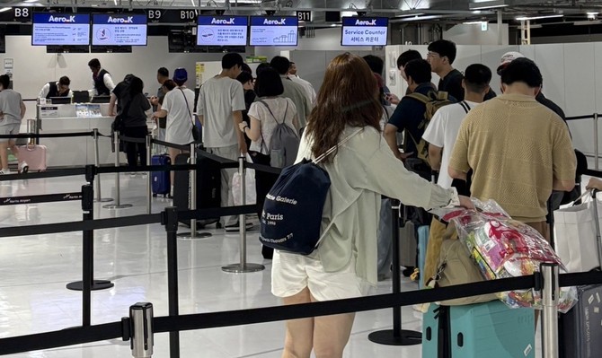 청주국제공항 체크인 카운터 앞에서 여행객들이 줄을 서서 수속을 기다리고 있다. 여름 휴가철을 맞아 공항은 떠나는 사람들로 북적이고 있다. ⓒ 에어로케이항공