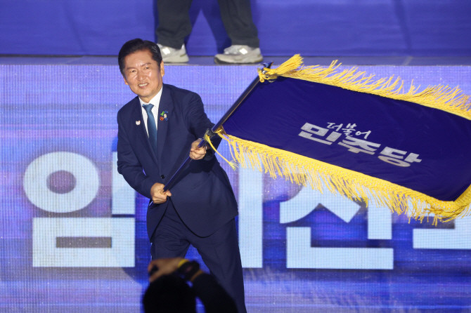 정청래 더불어민주당 신임 당 대표가 2일 고양 킨텍스에서 열린 전국당원대회에서 김병기 당 대표 직무대행 겸 원내대표로부터 받은 당기를 흔들고 있다. © 연합뉴스