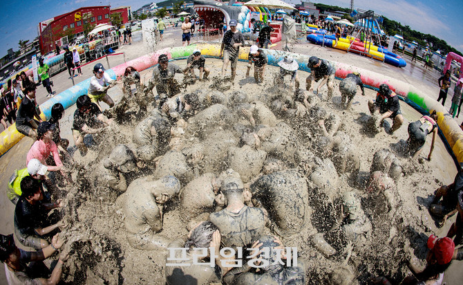 한여름 햇살 아래 보령머드축제 머드광장에서 원형으로 둘러앉은 참가자들이 온몸을 진흙에 묻힌 채 다양한 퍼포먼스를 펼치며, 역동적이고 이색적인 축제의 열기를 전하고있다. ⓒ 프라임경제
