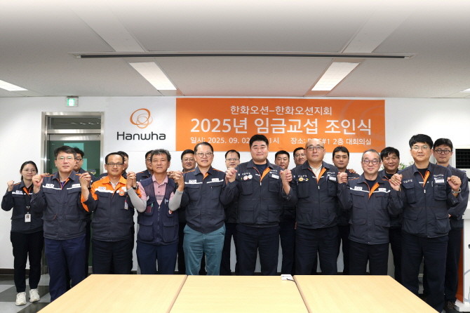 김희철 한화오션 대표이사(앞줄 왼쪽에서 네 번째)와 김유철 전국금속노조 경남지부 한화오션지회 지회장(앞줄 왼쪽에서 다섯 번째) 등 노사 교섭위원들이 두 손을 잡고 상생을 다짐하고 있다. ⓒ 한화오션