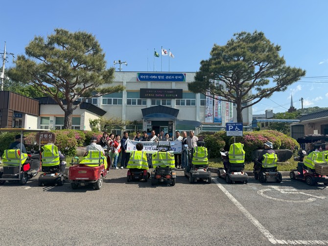 합천군 초계면이 면사무소 주차장에서 전동 휠체어와 스쿠터를 이용하는 어르신들의 교통사고 예방을 위해 '반딧불 전동차 지원사업'을 진행하고 기념촬영을 하고 있다. ⓒ 합천군